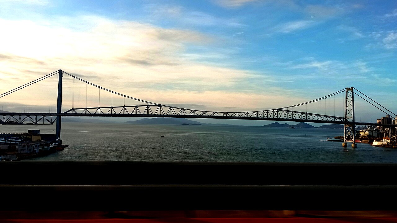 Ponte Hercílio Luz sobre a baía de Florianópolis, com a cidade ao fundo